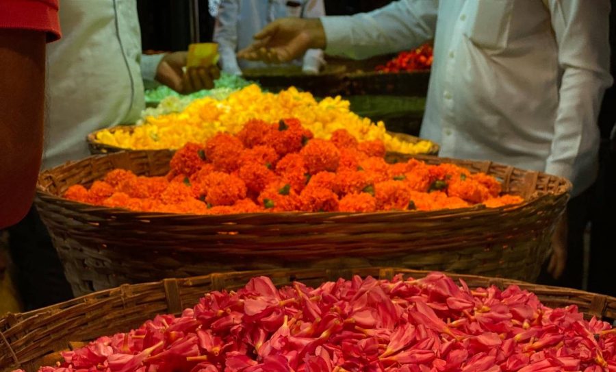 bowls of colourful flowers and men exchanging money in the background